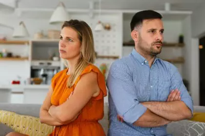 Sad pensive couple thinking of relationships problems sitting on sofa, conflicts in marriage